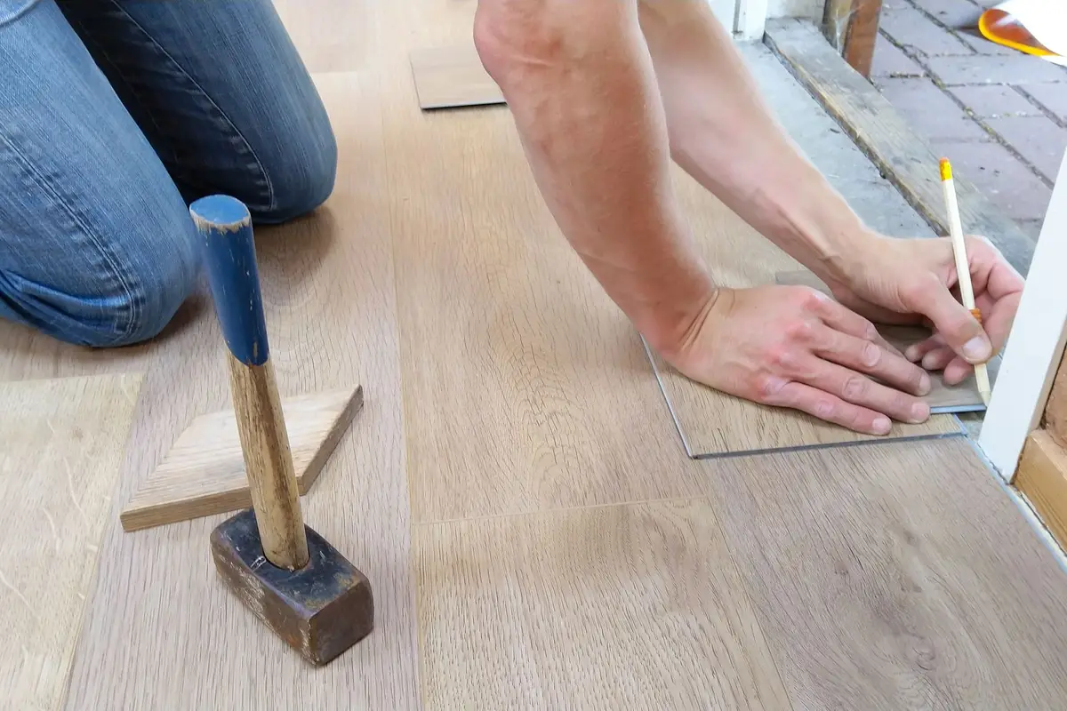 Flooring installer measuring and marking wood planks