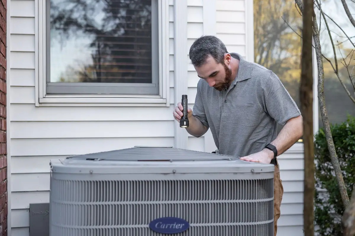 HVAC technician servicing an outdoor air conditioning condenser
